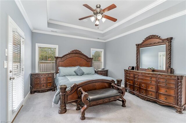 bedroom with a tray ceiling, multiple windows, light carpet, and ceiling fan