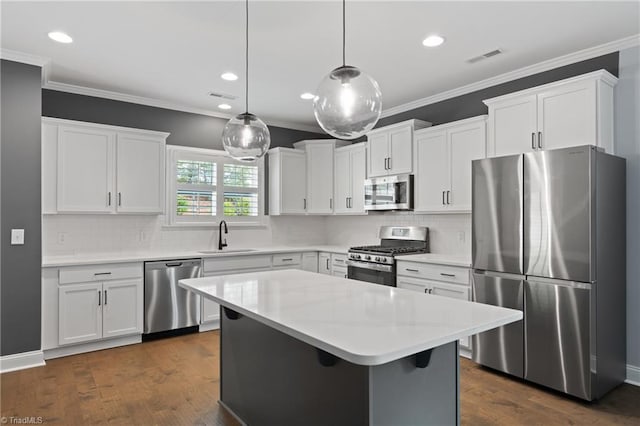 6823 Magnolia Park Ct, Clemmons, NC 27012 - kitchen featuring appliances with stainless steel finishes, white cabinetry, light countertops, ornamental molding, and a kitchen island