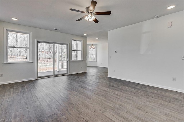 spare room with dark hardwood / wood-style flooring and ceiling fan with notable chandelier