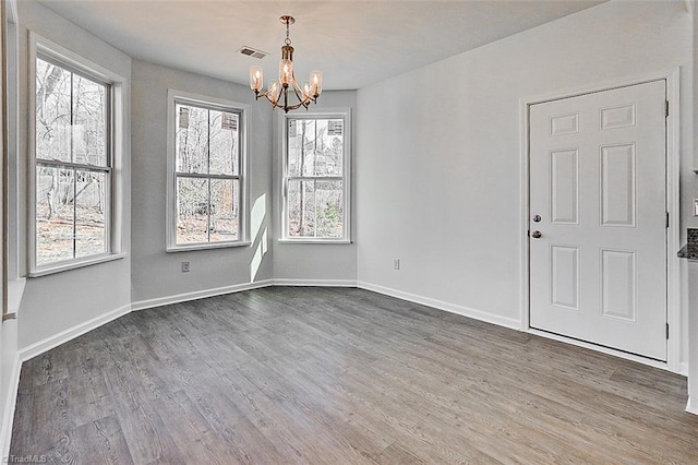 unfurnished dining area with dark wood-type flooring and an inviting chandelier