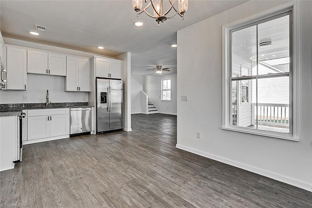 kitchen featuring white cabinetry, dark hardwood / wood-style floors, stainless steel appliances, and ceiling fan with notable chandelier