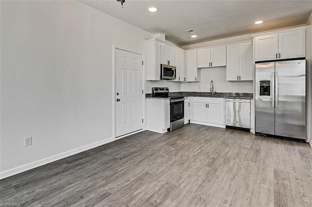 kitchen featuring wood-type flooring, white cabinetry, stainless steel appliances, and sink