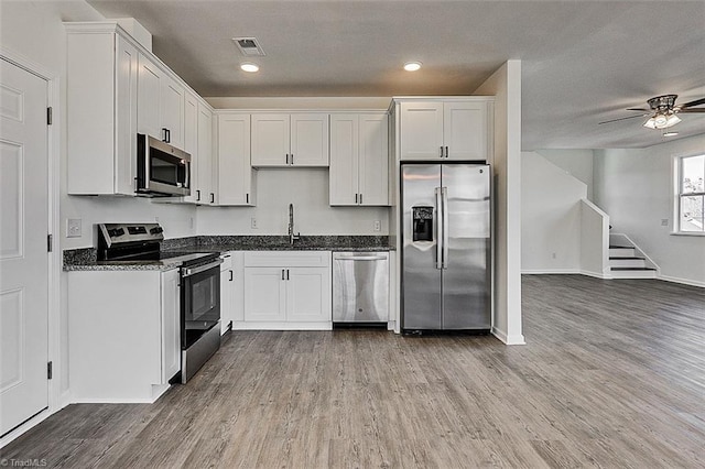 kitchen with appliances with stainless steel finishes, light hardwood / wood-style flooring, sink, and white cabinets