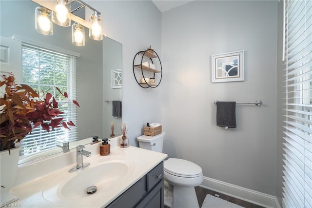 bathroom featuring a notable chandelier, vanity, and toilet