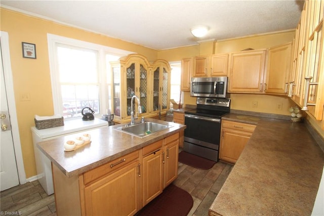 kitchen with a kitchen island with sink, light brown cabinetry, sink, and appliances with stainless steel finishes