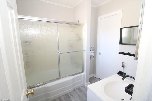 bathroom with hardwood / wood-style floors, bath / shower combo with glass door, and sink