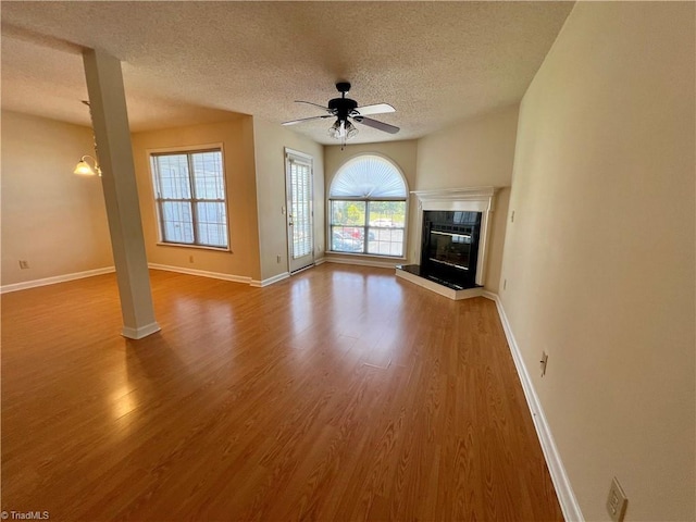 3638 Morris Farm Dr, Greensboro, NC 27409 - unfurnished living room featuring a textured ceiling, wood finished floors, ceiling fan, baseboards, and a glass covered fireplace