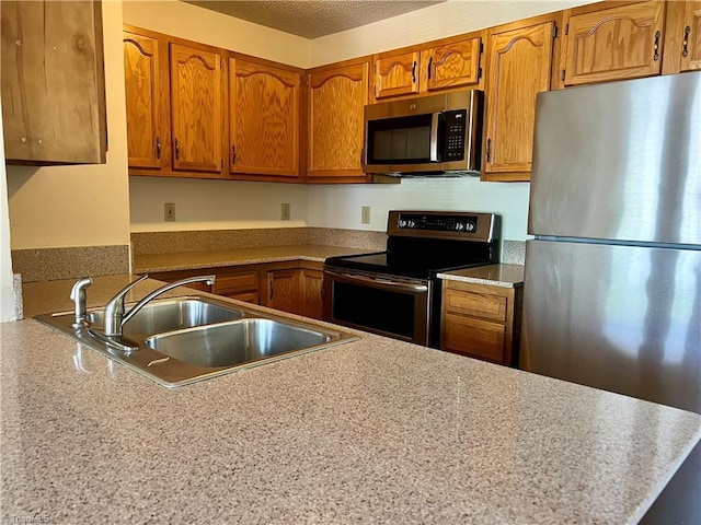 3638 Morris Farm Dr, Greensboro, NC 27409 - kitchen with appliances with stainless steel finishes, a sink, brown cabinetry, a peninsula, and light countertops