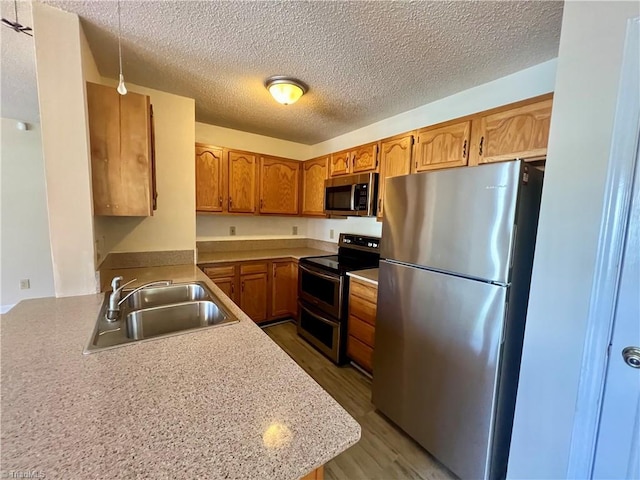 3638 Morris Farm Dr, Greensboro, NC 27409 - kitchen featuring appliances with stainless steel finishes, a sink, brown cabinetry, light countertops, and a textured ceiling
