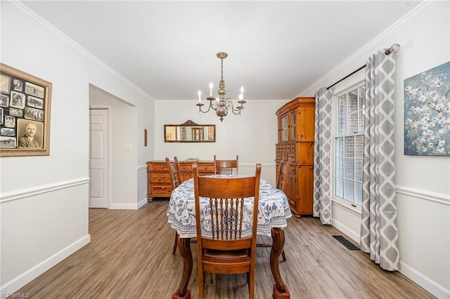 1101 Shalimar Ct, High Point, NC 27262 - dining area with baseboards, a chandelier, crown molding, light wood-type flooring, and plenty of natural light