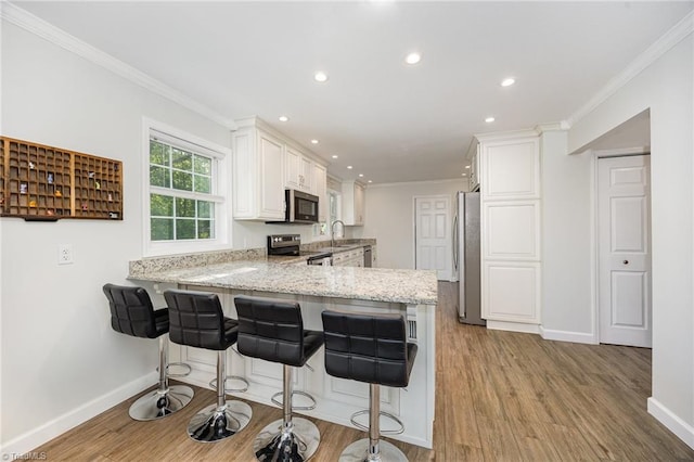 1101 Shalimar Ct, High Point, NC 27262 - kitchen featuring appliances with stainless steel finishes, a peninsula, a sink, baseboards, and white cabinets
