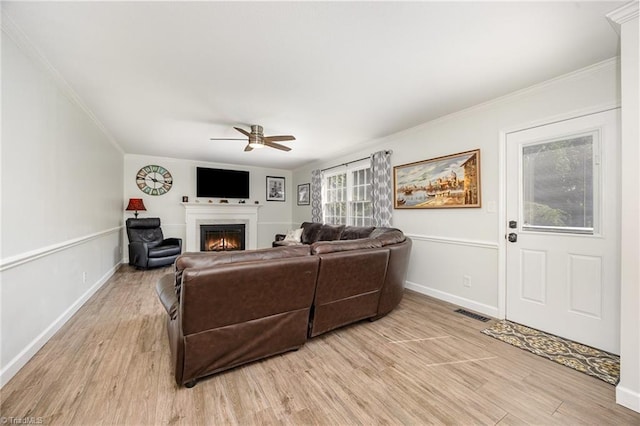 1101 Shalimar Ct, High Point, NC 27262 - living room featuring a ceiling fan, a lit fireplace, light wood-type flooring, ornamental molding, and baseboards