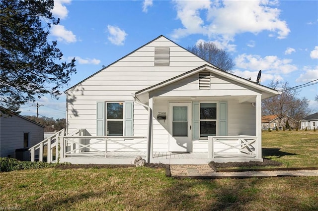 rear view of house featuring covered porch and a lawn