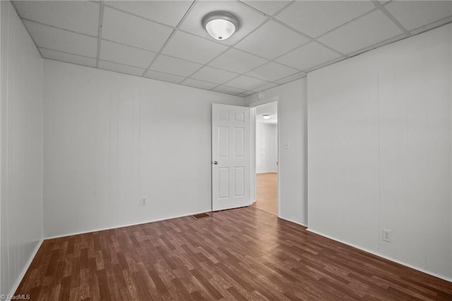 unfurnished room with a drop ceiling, wood finished floors, and visible vents