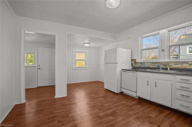 kitchen featuring white appliances, decorative backsplash, dark countertops, dark wood-style floors, and a sink