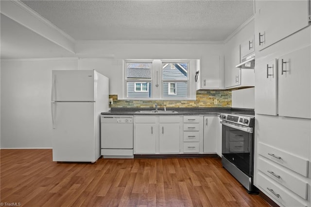 kitchen with dark countertops, ornamental molding, a sink, wood finished floors, and white appliances