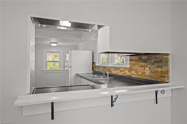 kitchen with freestanding refrigerator, a sink, and decorative backsplash