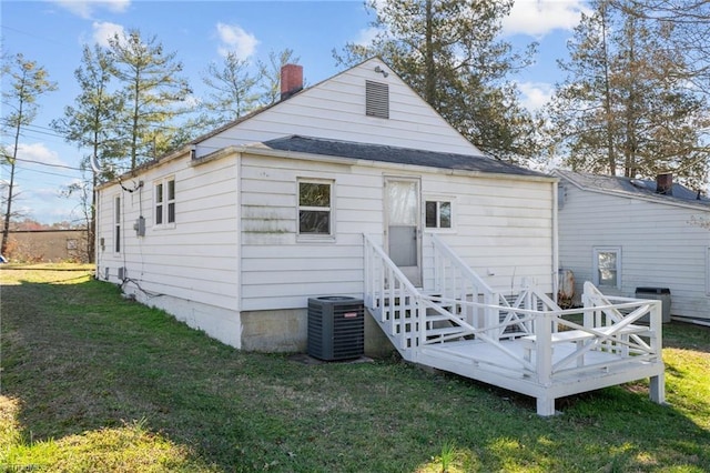 rear view of property with a chimney, central AC unit, and a yard