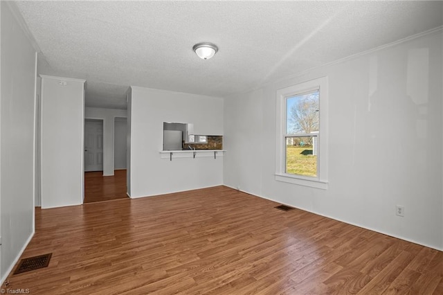 unfurnished living room featuring visible vents, a textured ceiling, and wood finished floors