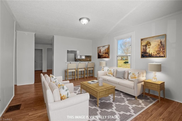 living room with a textured ceiling, visible vents, and wood finished floors