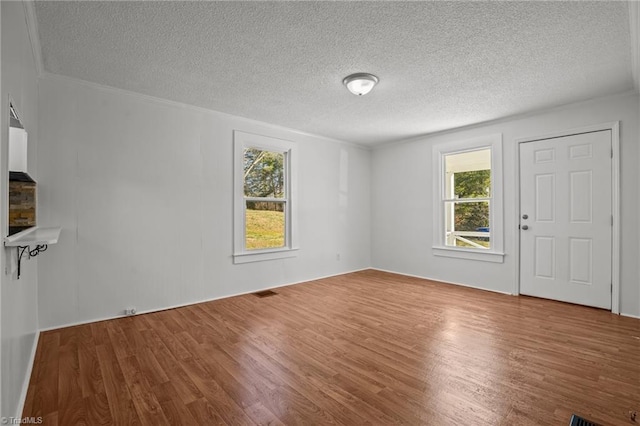 unfurnished living room with a textured ceiling, visible vents, and wood finished floors