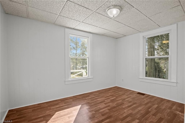 empty room featuring a paneled ceiling, visible vents, and wood finished floors