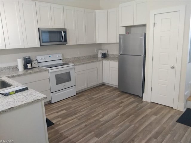 kitchen featuring white cabinets, stainless steel appliances, light stone counters, and dark hardwood / wood-style floors