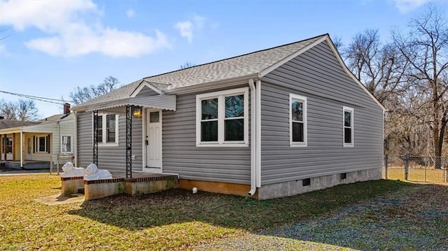 view of front facade featuring a front lawn, crawl space, a shingled roof, and fence