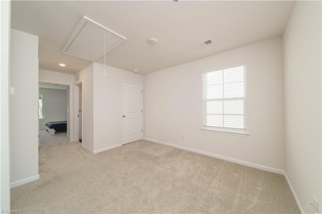 spare room with visible vents, recessed lighting, baseboards, light colored carpet, and attic access