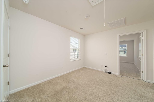 unfurnished bedroom featuring visible vents, multiple windows, attic access, and carpet