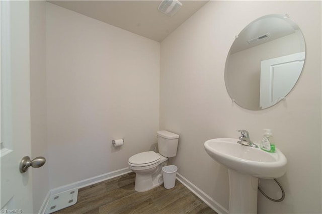 bathroom featuring visible vents, baseboards, toilet, and wood finished floors