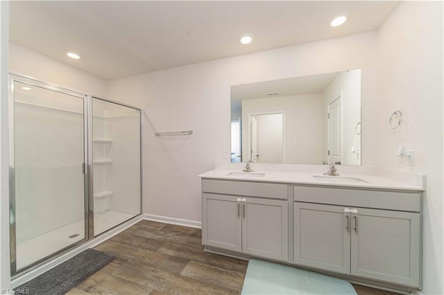 full bath with a sink, wood finished floors, and a stall shower