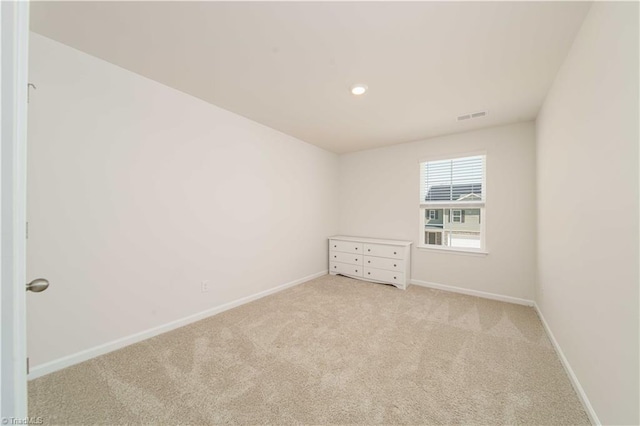 spare room featuring light carpet, visible vents, and baseboards