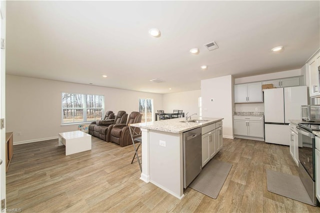 kitchen with visible vents, a kitchen island with sink, open floor plan, appliances with stainless steel finishes, and light wood finished floors