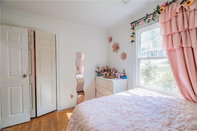 bedroom featuring crown molding and light wood finished floors