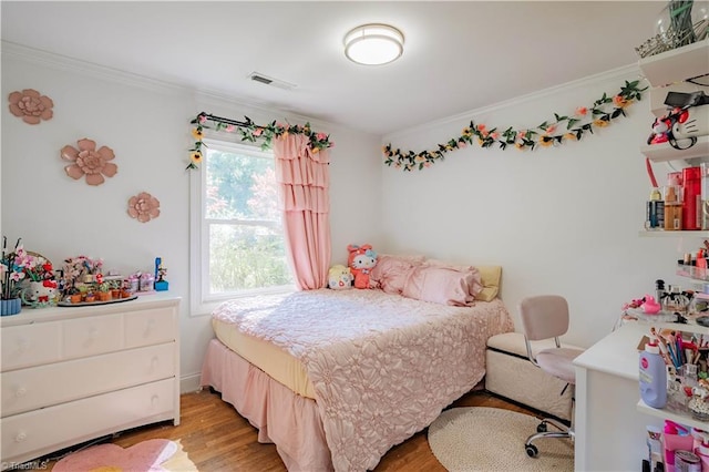bedroom featuring ornamental molding, light wood-style floors, and visible vents