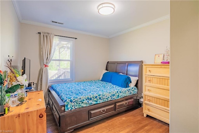 bedroom featuring crown molding, wood finished floors, and visible vents