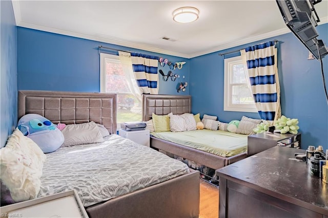 bedroom featuring ornamental molding, wood finished floors, and visible vents