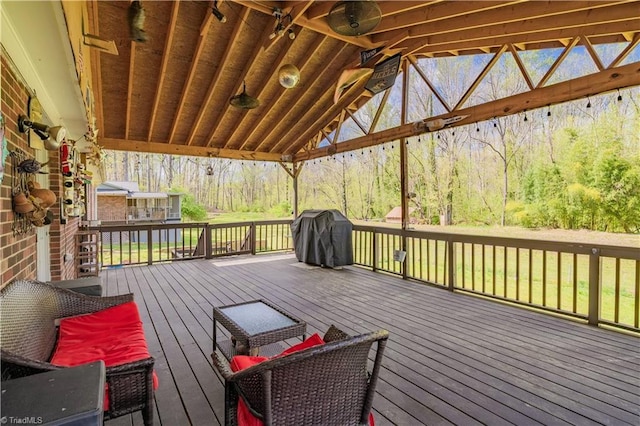 wooden deck with a view of trees and area for grilling