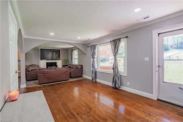 living area with ornamental molding, wood finished floors, visible vents, and plenty of natural light