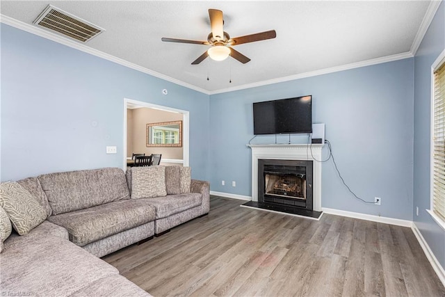 1515 Klompen Rd, Kernersville, NC 27284 - living room with wood finished floors, ceiling fan, a fireplace with raised hearth, ornamental molding, and baseboards