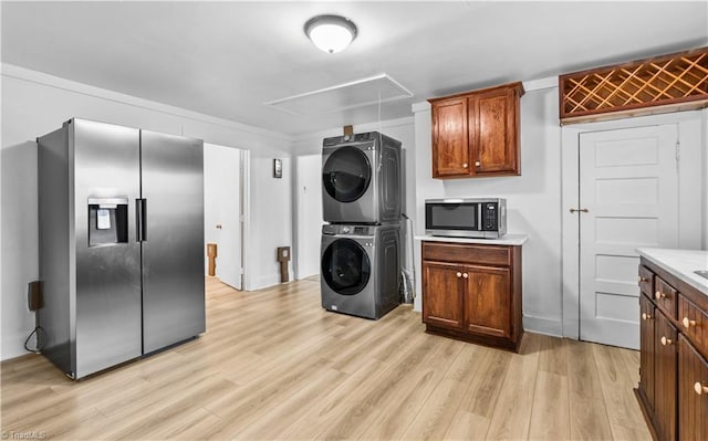 washroom with light wood-type flooring and stacked washing maching and dryer