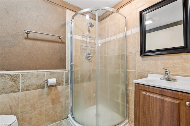 bathroom with vanity, tile walls, and a shower with shower door