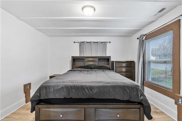 bedroom featuring beamed ceiling and light hardwood / wood-style flooring