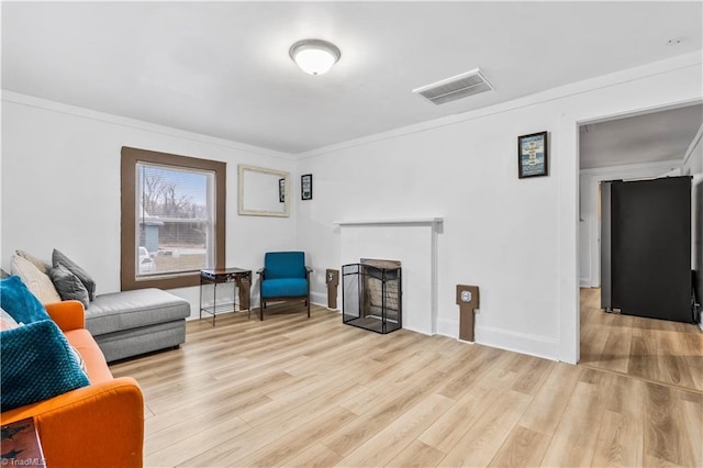 living room featuring a wood stove, light hardwood / wood-style flooring, and ornamental molding