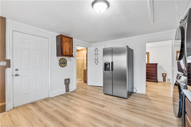 kitchen with stainless steel fridge, light wood-type flooring, and stacked washer and clothes dryer