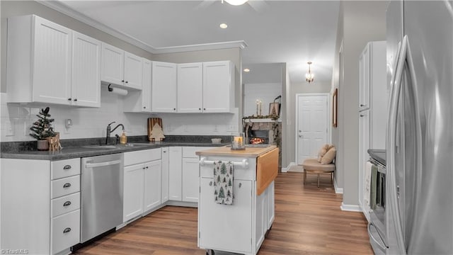 kitchen with white cabinetry, sink, light wood-type flooring, appliances with stainless steel finishes, and ornamental molding