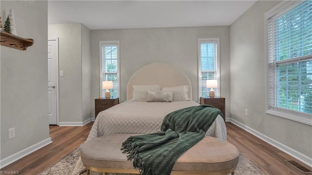 bedroom with dark hardwood / wood-style flooring and multiple windows