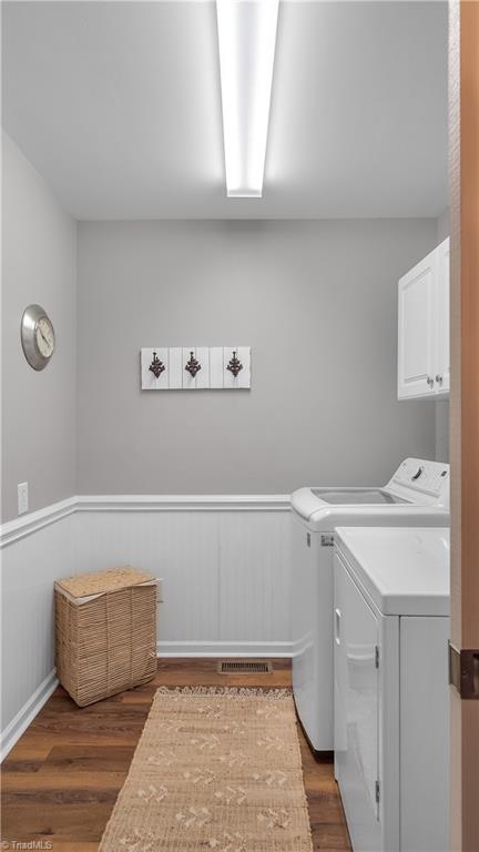 washroom featuring cabinets, washer and clothes dryer, and dark wood-type flooring