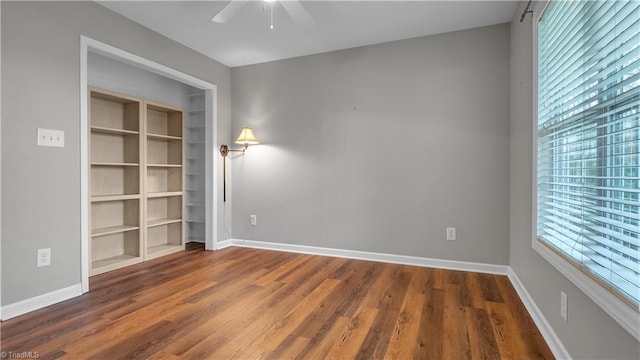 empty room featuring a wealth of natural light, ceiling fan, and dark wood-type flooring